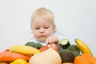 A baby boy looking at a stack of fruit and vegetables --- Image by © Image Source/Corbis