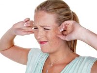 a young woman holds her fingers in her ears. loudness and tinnitus.,